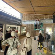 Visite de chantier à Rountzenheim-Auenheim : des personnes observent un ouvrier sur une échelle au site de construction.