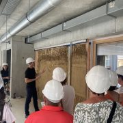 Visiteurs en casques de sécurité devant un mur lors de la visite de chantier du groupe scolaire à Rountzenheim-Auenheim.