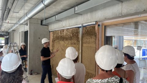 Visiteurs en casques de sécurité devant un mur lors de la visite de chantier du groupe scolaire à Rountzenheim-Auenheim.