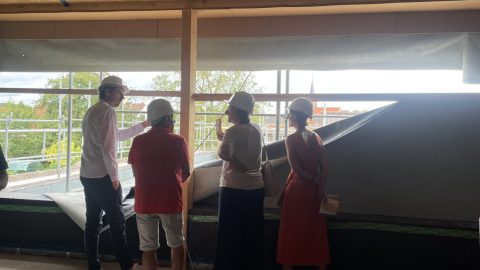 Groupe de personnes discutant devant une fenêtre lors de la visite de chantier du groupe scolaire à Rountzenheim-Auenheim