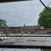 Toit en métal avec un bâtiment en arrière-plan, lors de la visite de chantier du groupe scolaire à Rountzenheim-Auenheim.