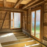 Intérieur d'une pièce aux murs en bois et fenêtres, représentant la réhabilitation d'une maison alsacienne à Mackenheim.